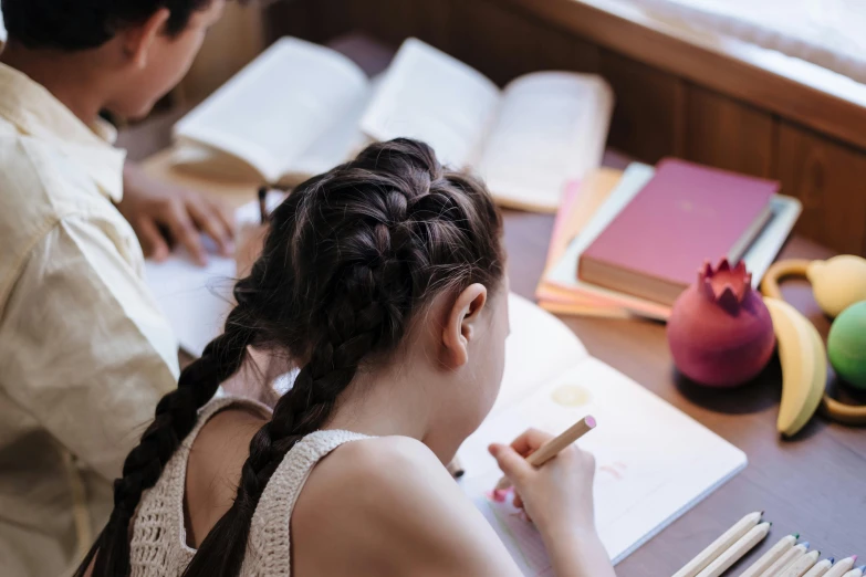 a girl sits at her desk with several books, an apple and a pencil