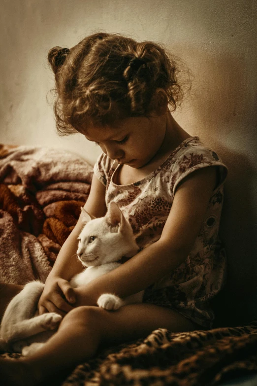the young child is holding a white cat