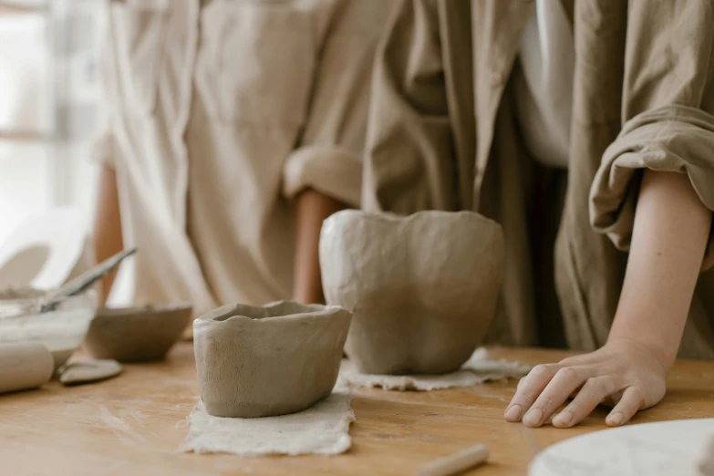 hands of someone making a vase from clay on a table