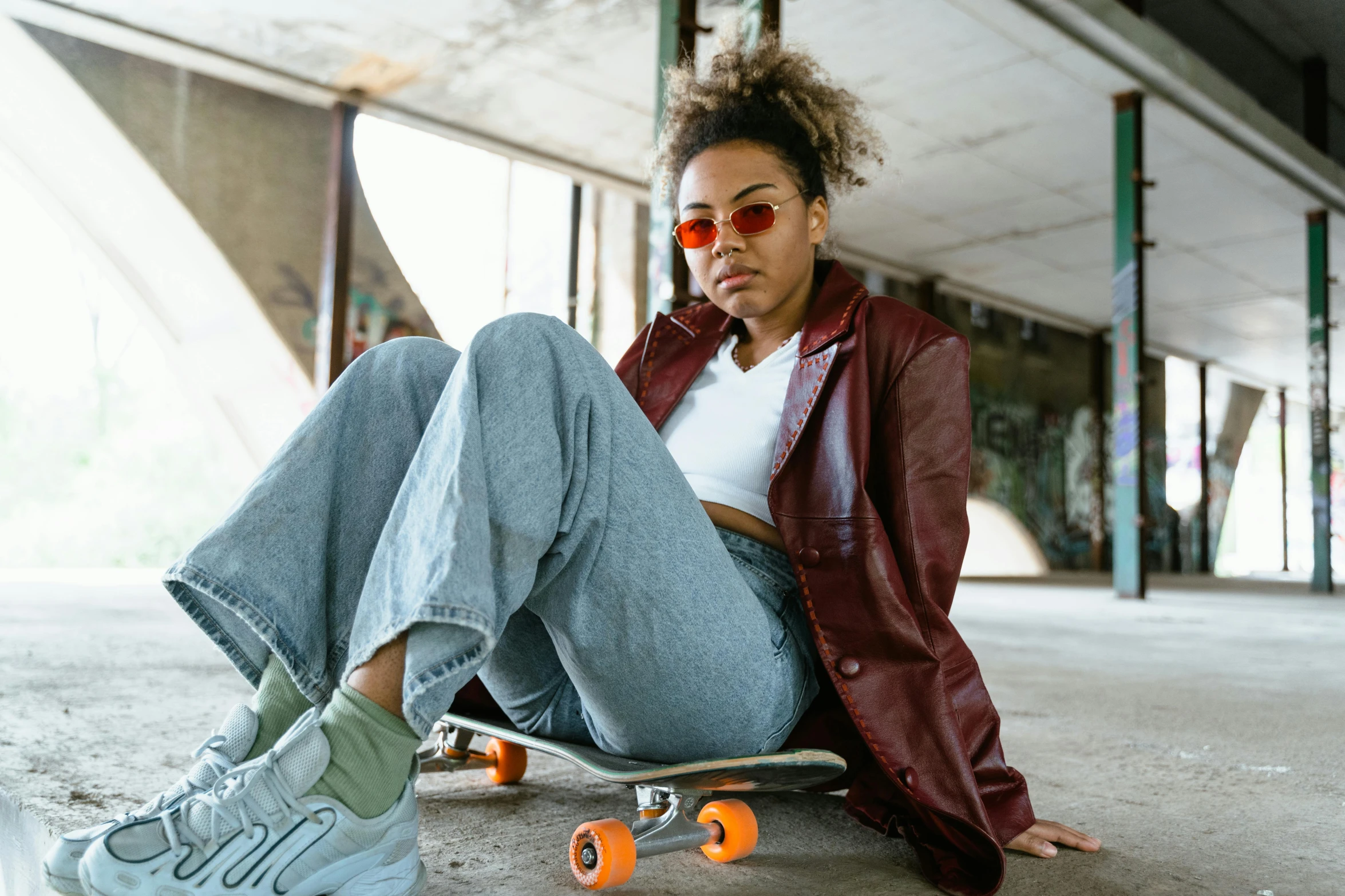 a woman in white shirt and red coat on skateboard