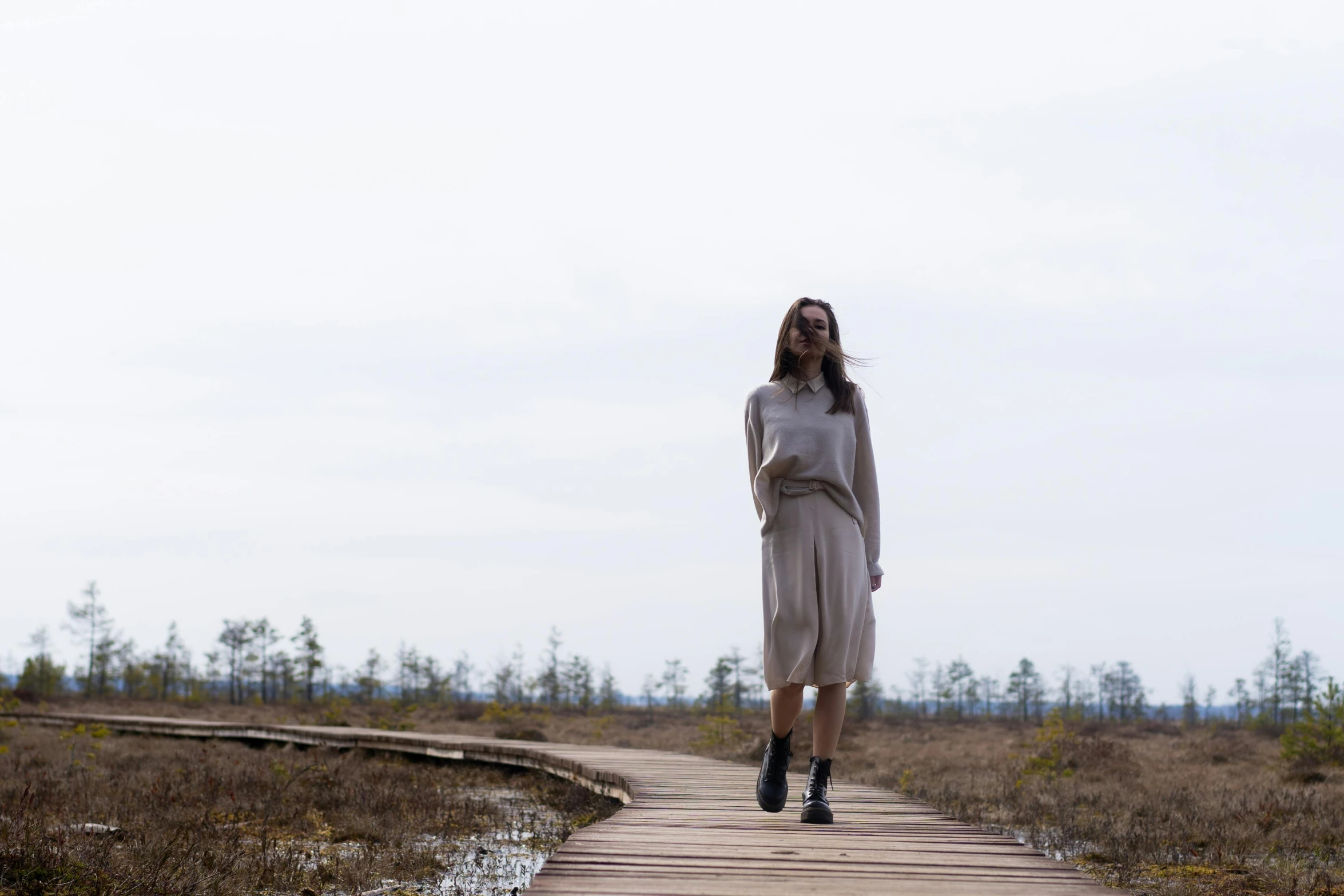 a woman in a dress walking down a boardwalk