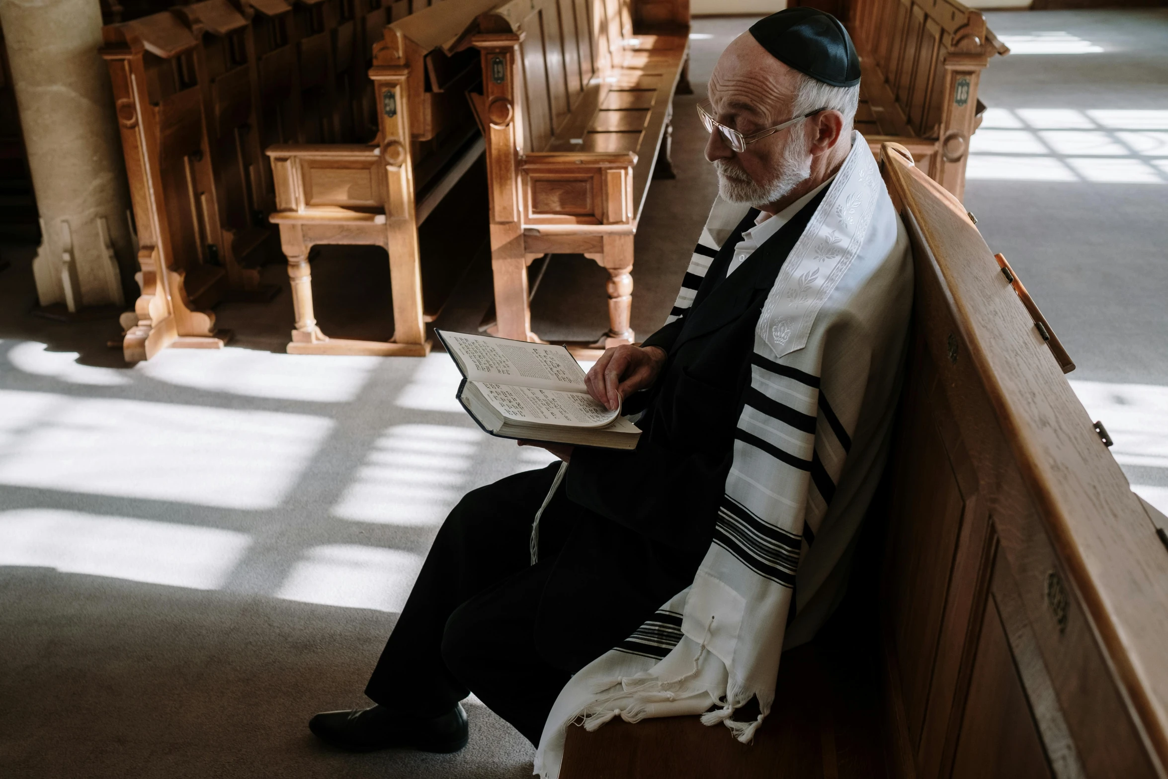 man sitting on a bench reading a book with his hands folded over it