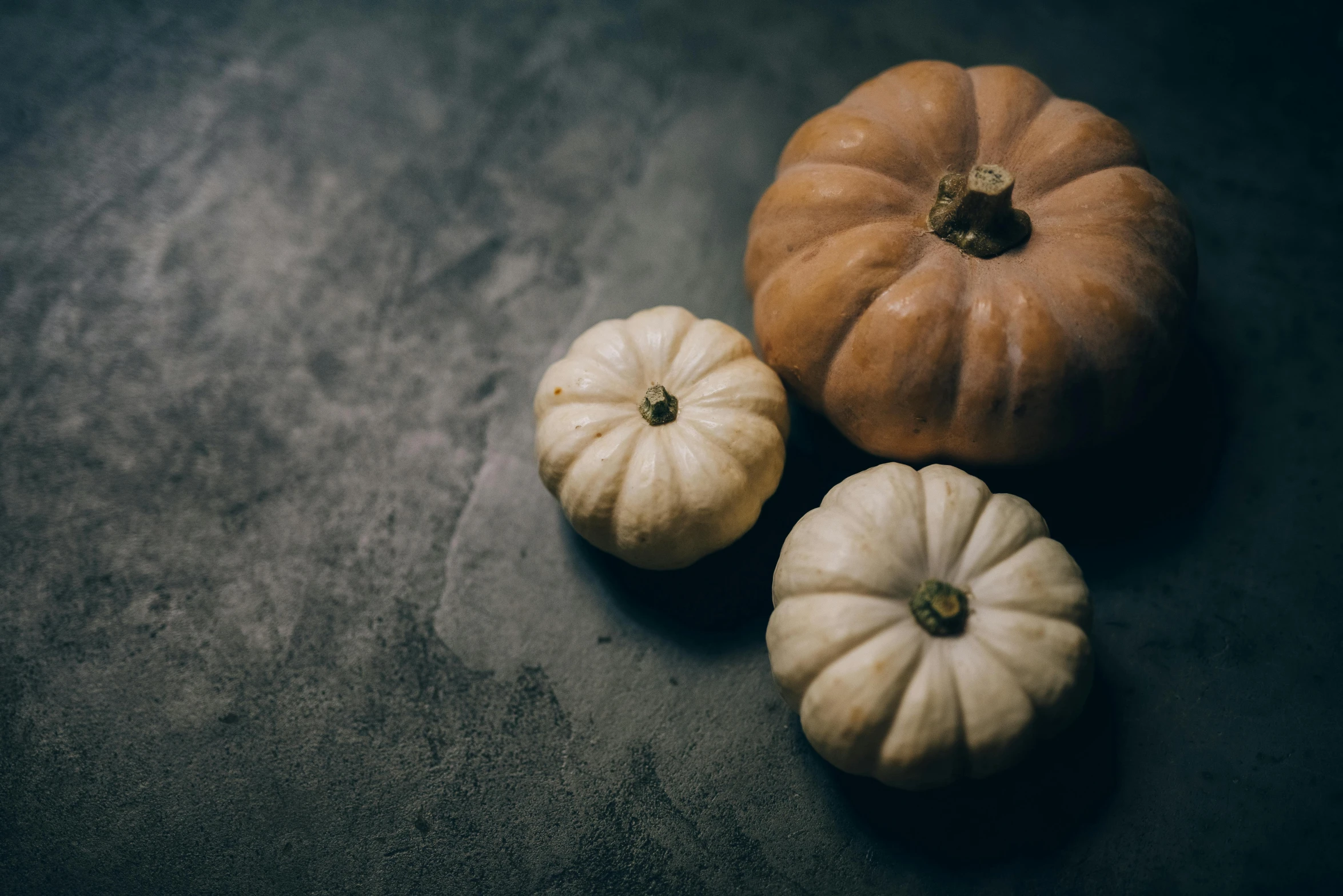 small orange pumpkins lie side by side on the floor