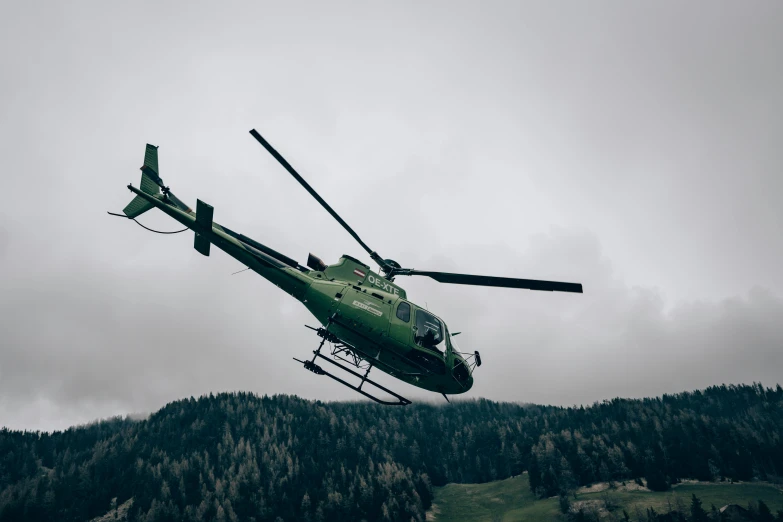 a helicopter that is in the air with mountains behind it