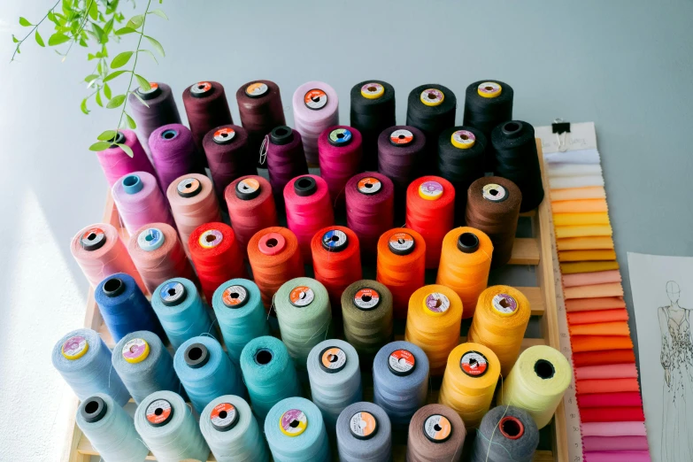 an assortment of brightly colored spools on wooden sticks