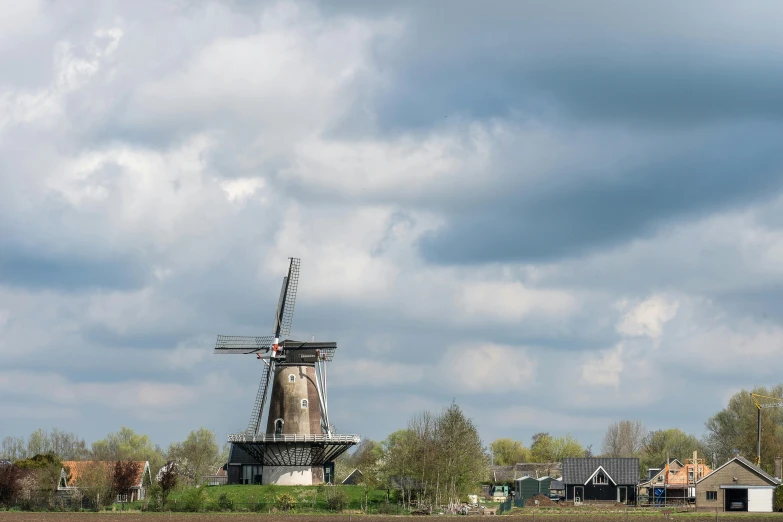 a windmill on the river surrounded by farm houses