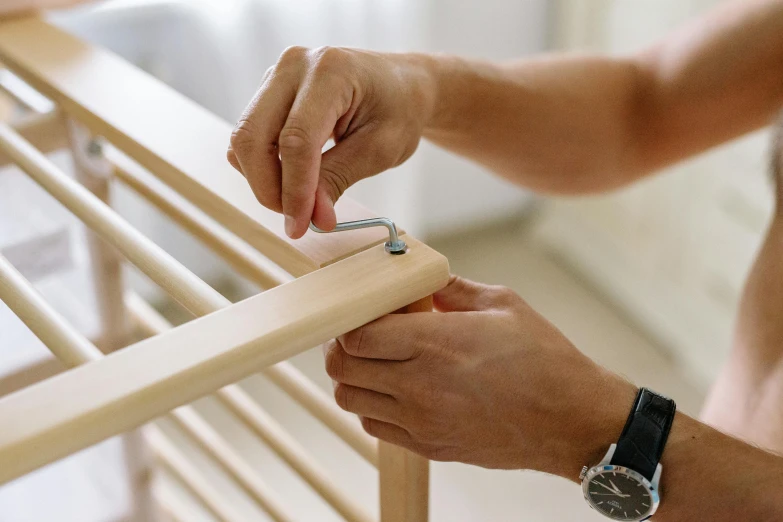 person holding an object up near the handrail of a baby crib