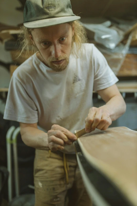 a man working on a wooden board next to a lot of tools