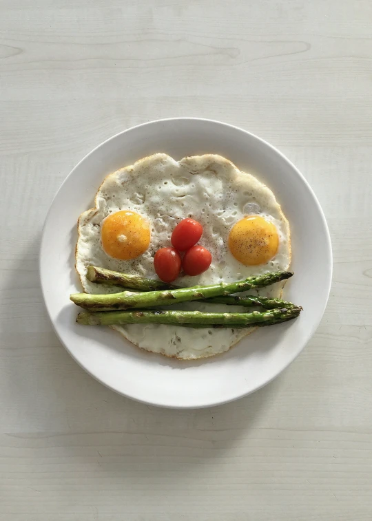 a close up of an egg and asparagus on a plate