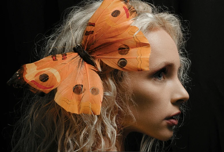 a woman with white hair wearing orange moths on her head