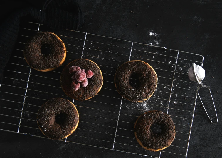 three donuts are decorated and have chocolate frosting and raspberries