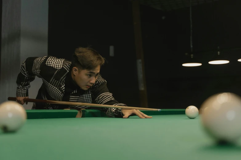 man in black shirt leaning over a pool table with pool cues