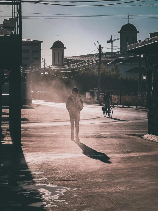 a man is walking down the street, just as someone rides their bike