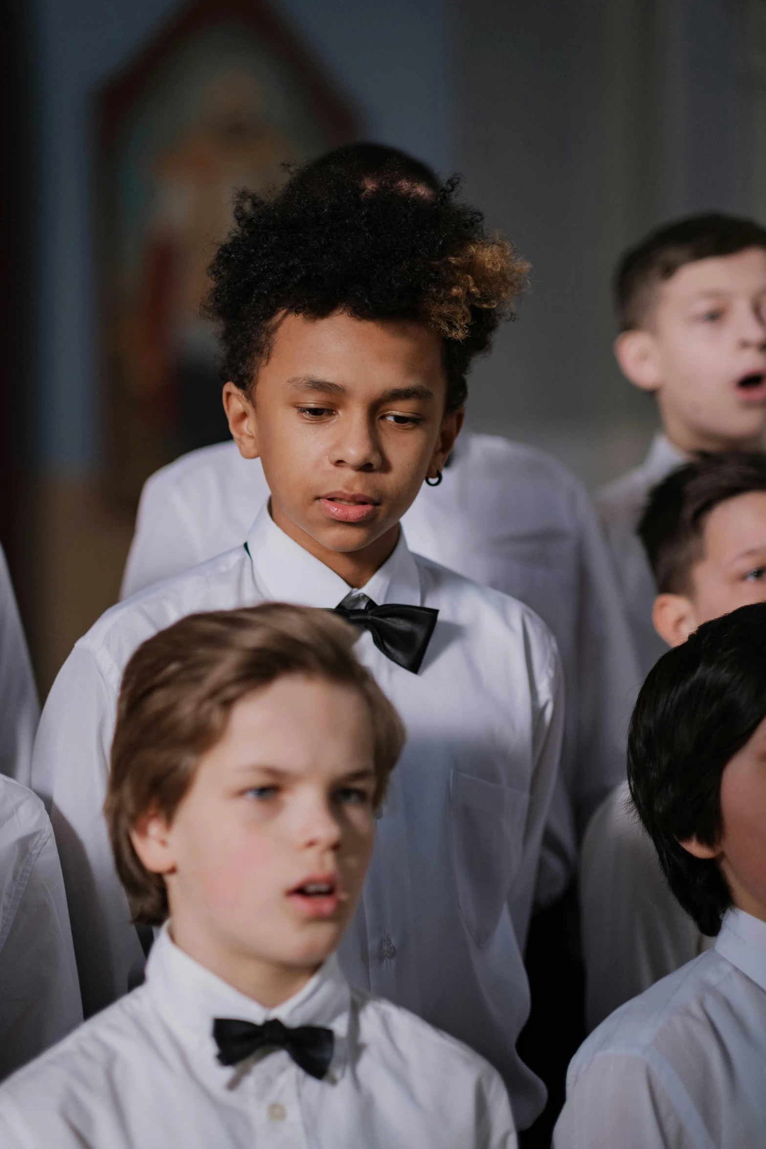 young men and women in formal wear stand close together with microphones in hand