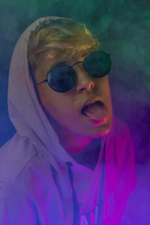 a woman in sunglasses blowing smoke with a hoodie