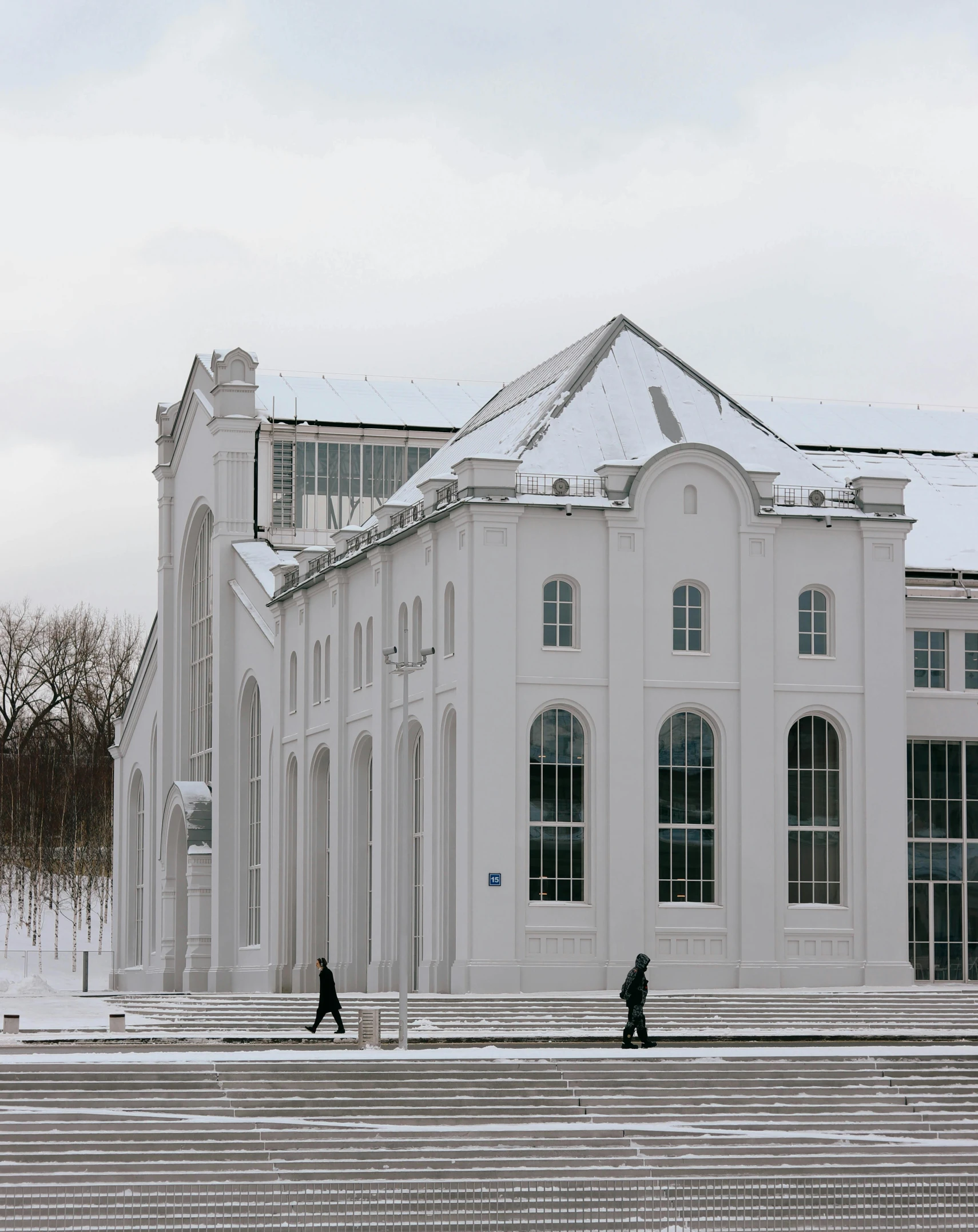 a white building in winter with stairs leading up to it