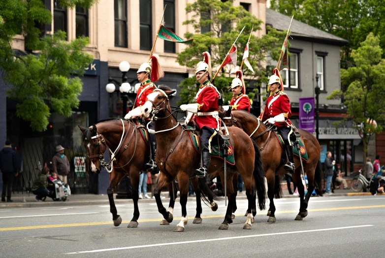 men in uniforms ride on horses on a city street