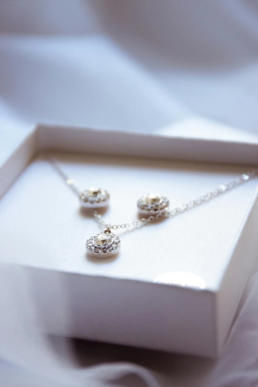 a pair of diamond earrings sitting inside a white box