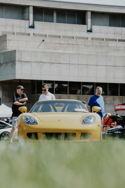 men in uniform next to a yellow sports car