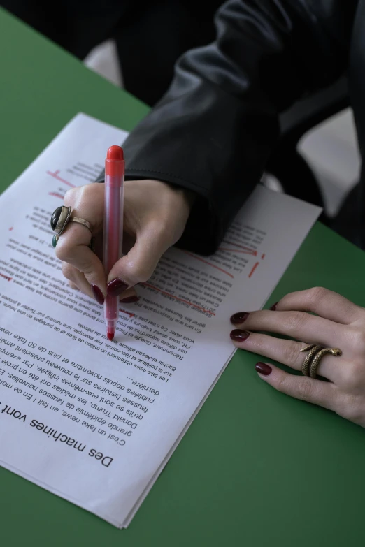 someone holding a pen next to a page of paper