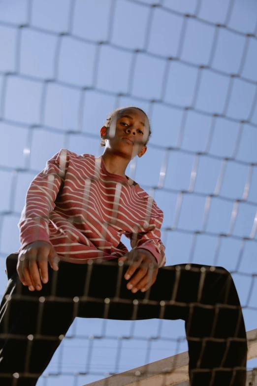 a man sitting on the side of a tall fence