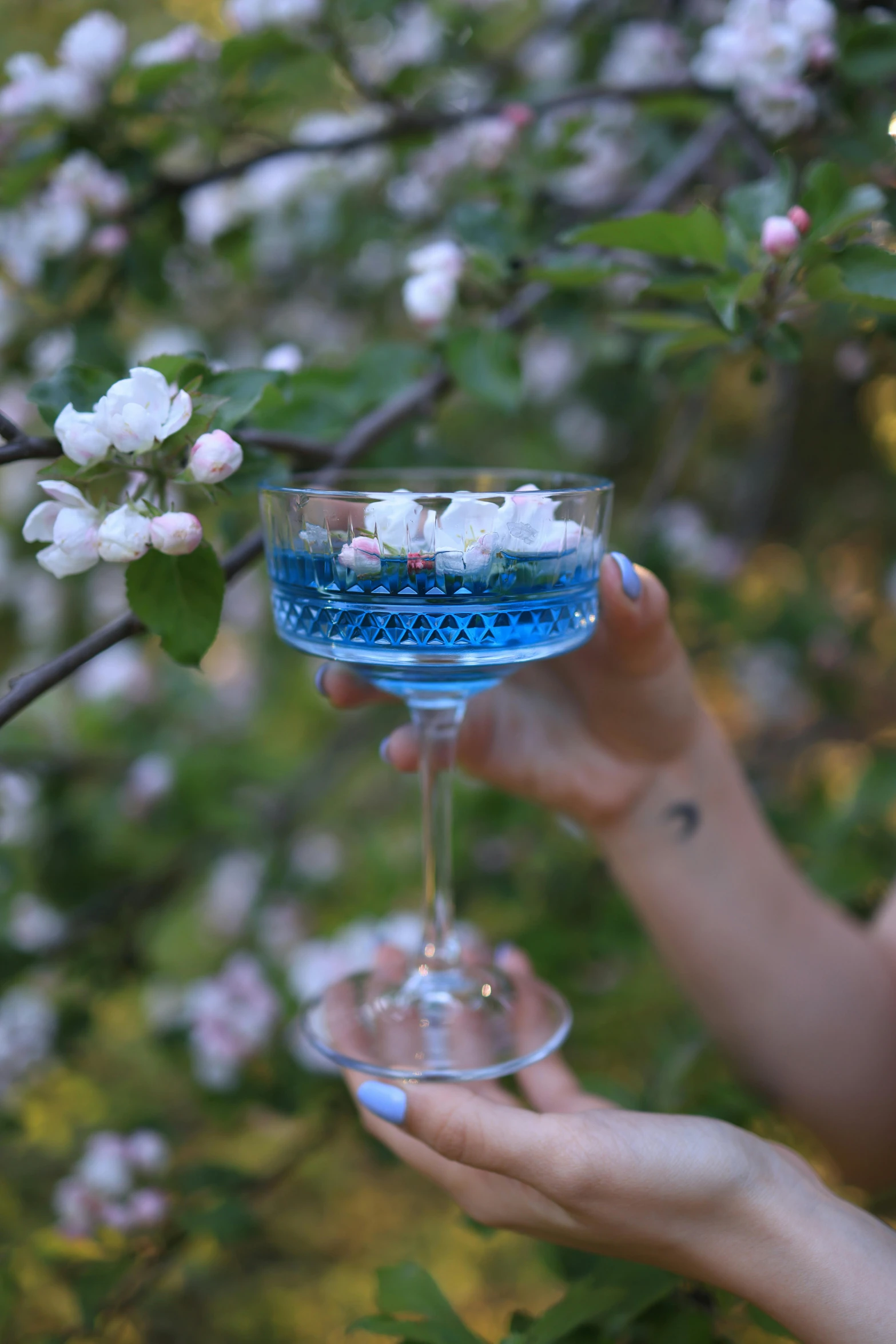 a woman holding up a martini in front of flowers