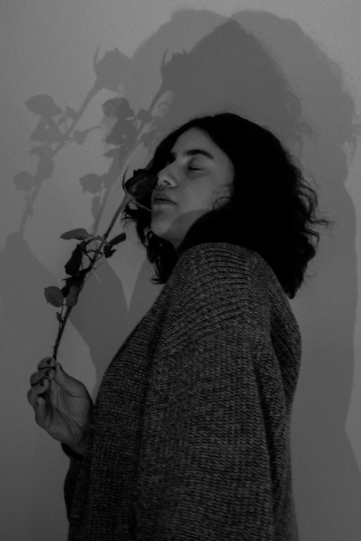 black and white po of a young woman with her face obscured by a flower