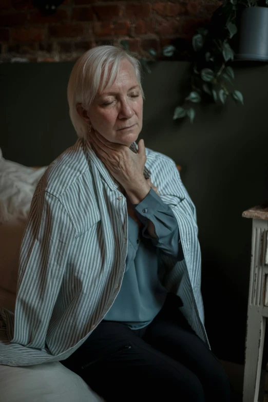 an elderly woman sitting on the couch in front of a clock