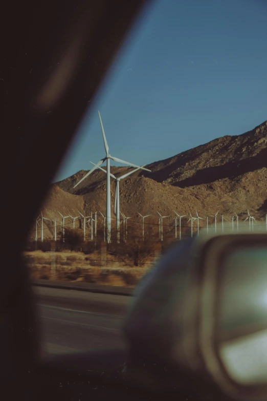 a wind farm in the desert with mountains in the background