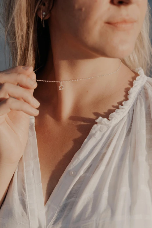 a woman in white dress holding onto her necklace