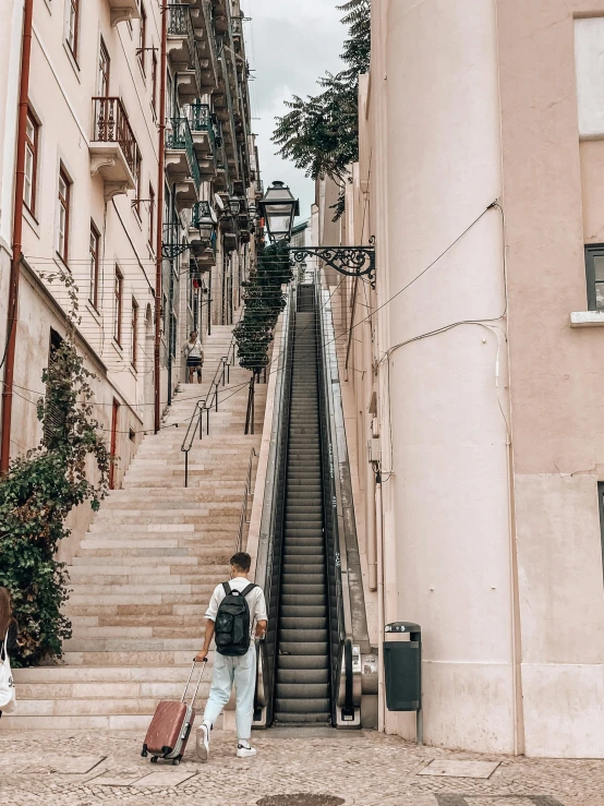 two people are walking up the stairs near their suitcases