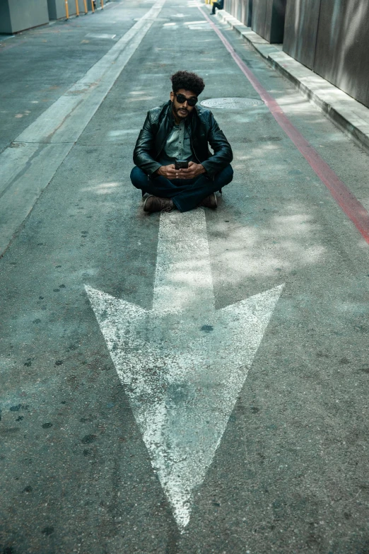 a man sitting on a street with a arrow drawn on it