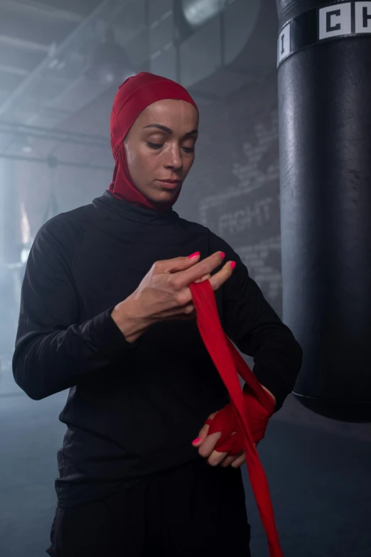 a woman standing in a gym holding a red ribbon