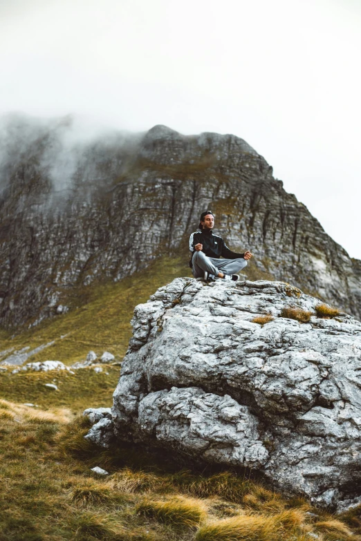 a man sits on top of a large rock