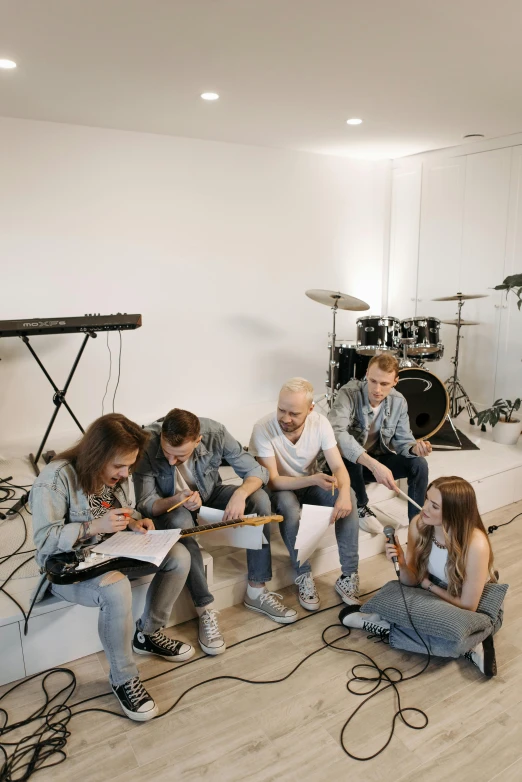 group of young people sitting on a couch playing music in a room