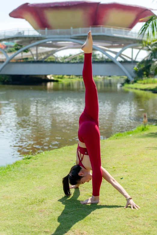 a young woman in red doing yoga on a field