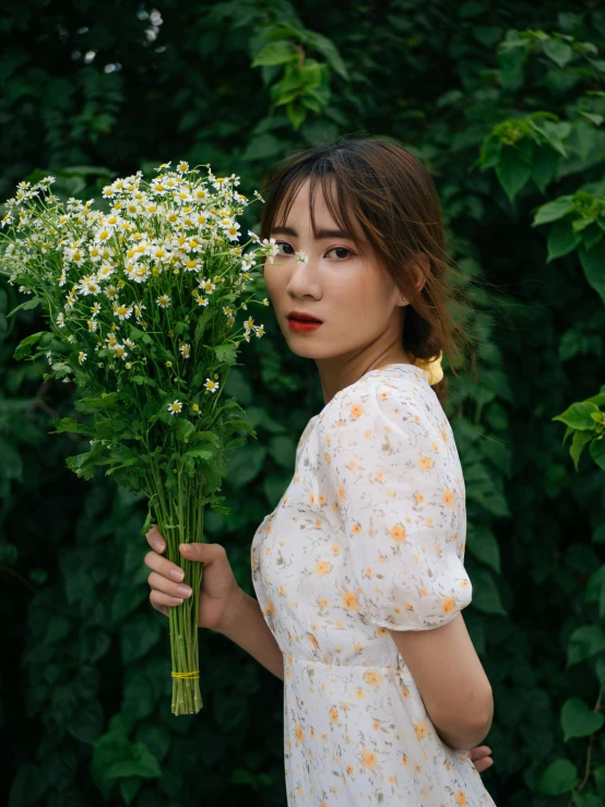 a woman holding a bouquet of daisies in front of her face