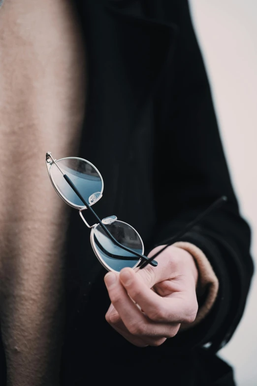 a man holding sunglasses in his right hand