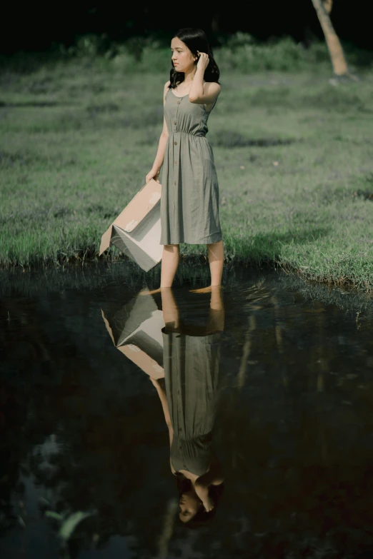 the woman is standing near a small river holding an umbrella