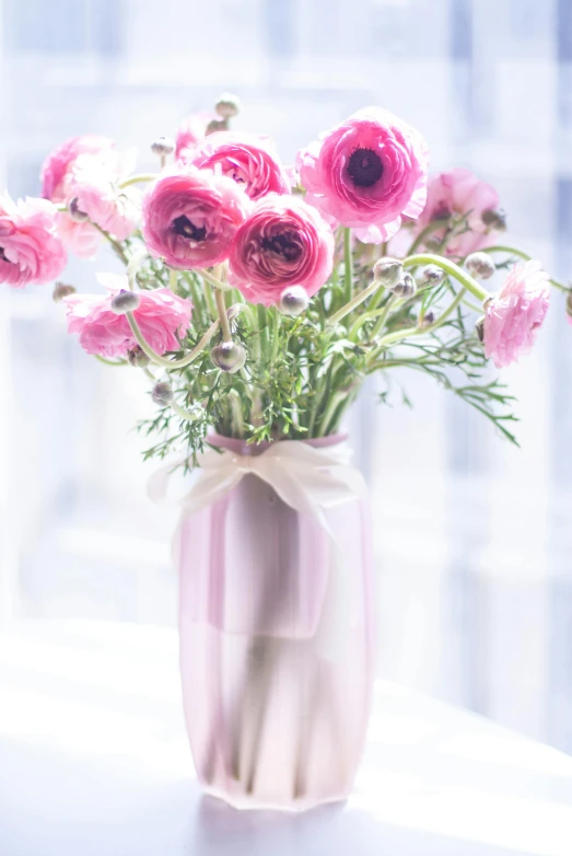 a vase of flowers with pink ribbons