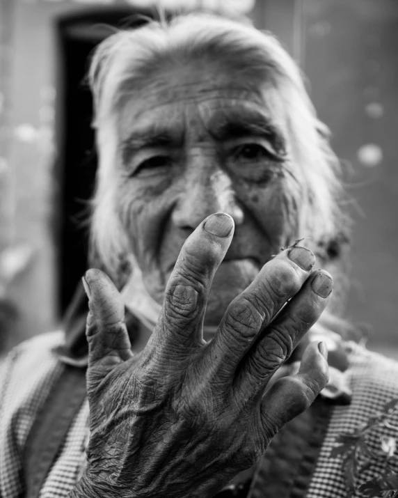 an old woman holds her hands in front of her face