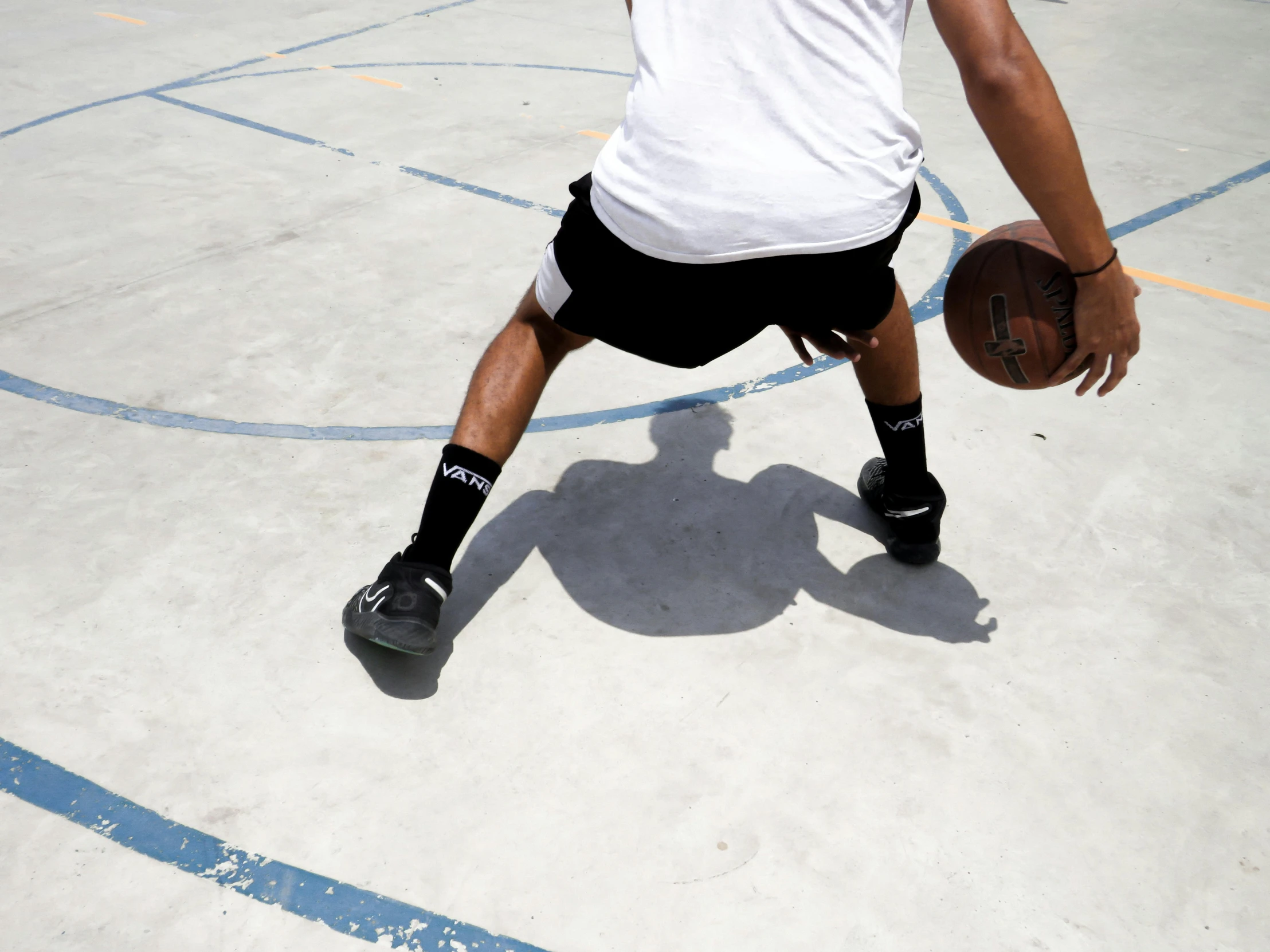 a young man is standing with his legs crossed, holding a basketball