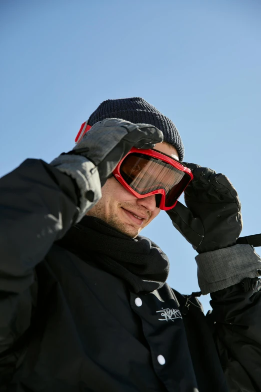 man in cold weather coat puts red sunglasses on his face