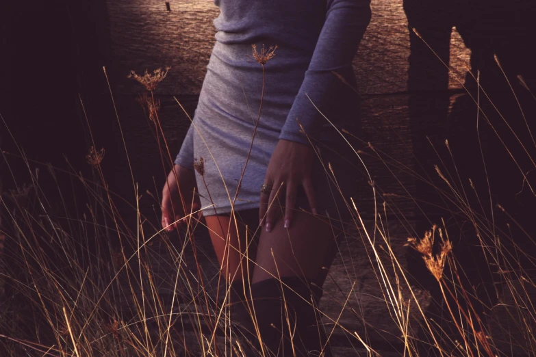 a woman standing in the tall grass next to a fire hydrant