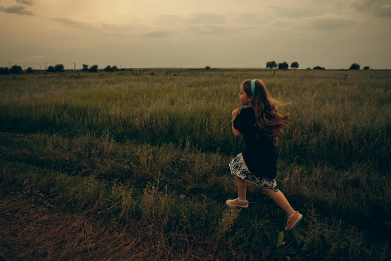 a woman walking through a field holding a frisbee