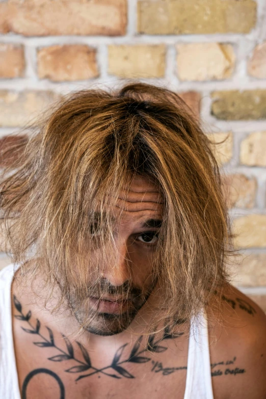 the man has long, blonde hair and tattoos on his head