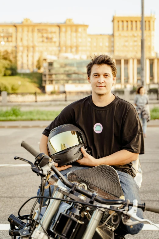 a man holding his motorcycle in one hand and a helmet on the other