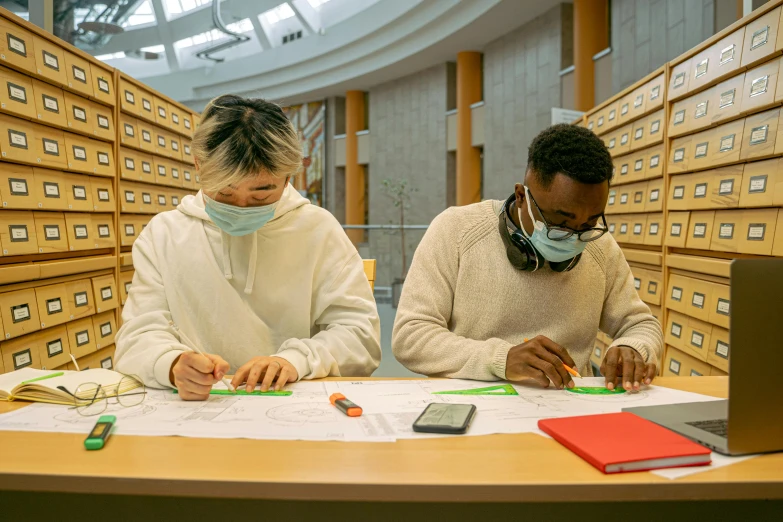 two people sitting at a table studying in a liry