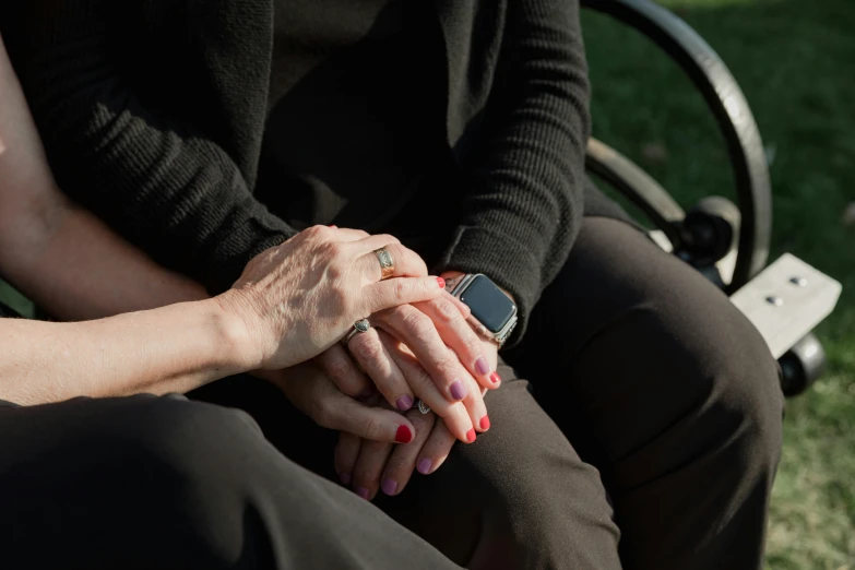 two woman with brown nails are holding hands