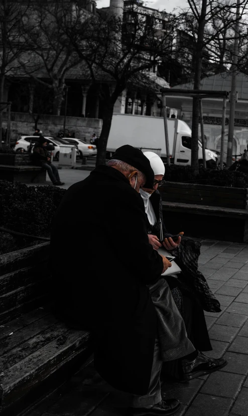 a man sits on a bench looking at his phone